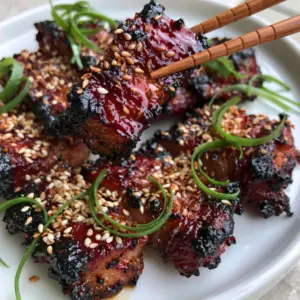 Thick slices of Chinese style pork with deep mahogany red glaze and blackened edges on a white plate. (Chinese style pork)